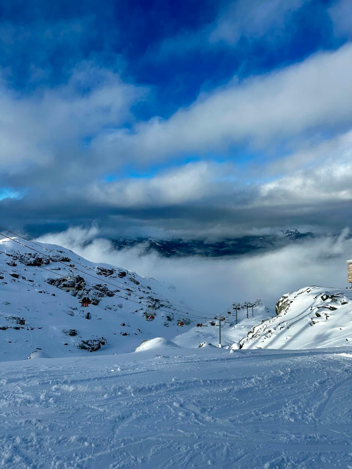 Snow-covered ridgeline beneath blue clouds at Whistler Blackcomb